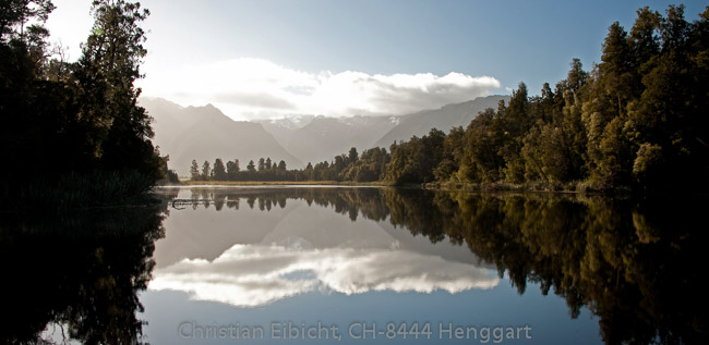 Morgenstimmung beim Lake Matheson auf der Südinsel.  Im HIntergrund der von Woken verhüllte Mount Cook.